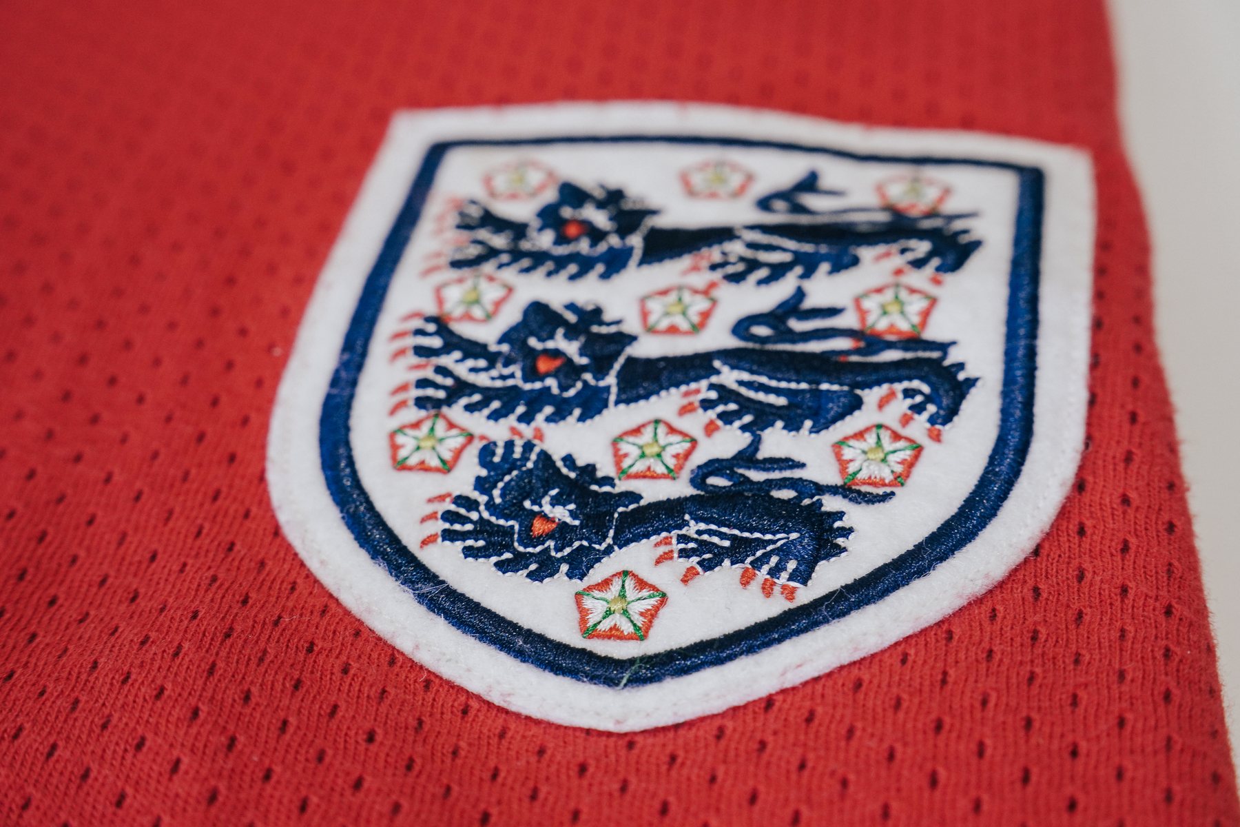 Close-up of an embroidered three lions crest on a red shirt