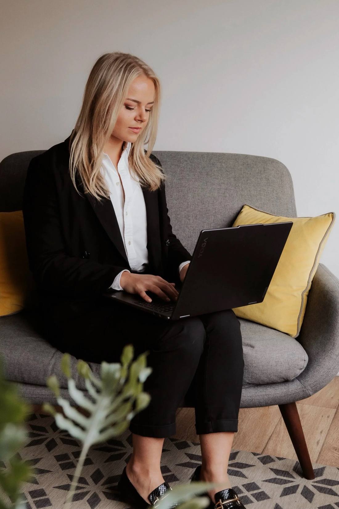 Holly James working on a laptop on a grey sofa