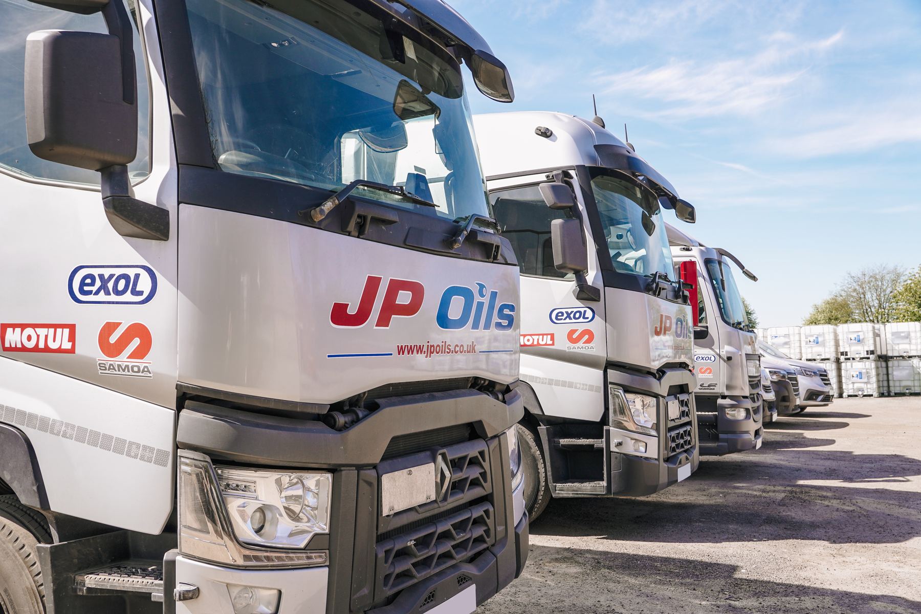 The JP Oils fleet lined up in the yard under a blue sky