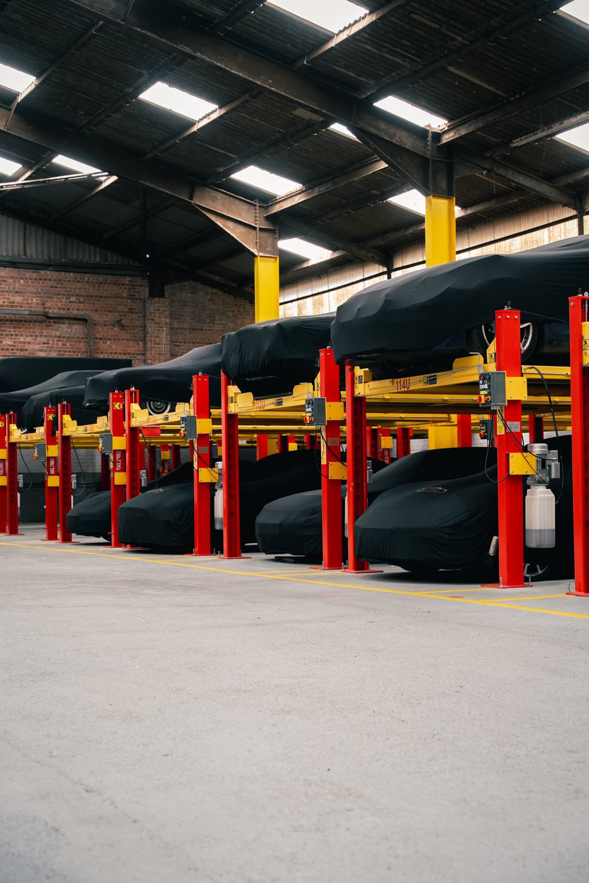 Rows of covered cars on lifts inside a large indoor facility