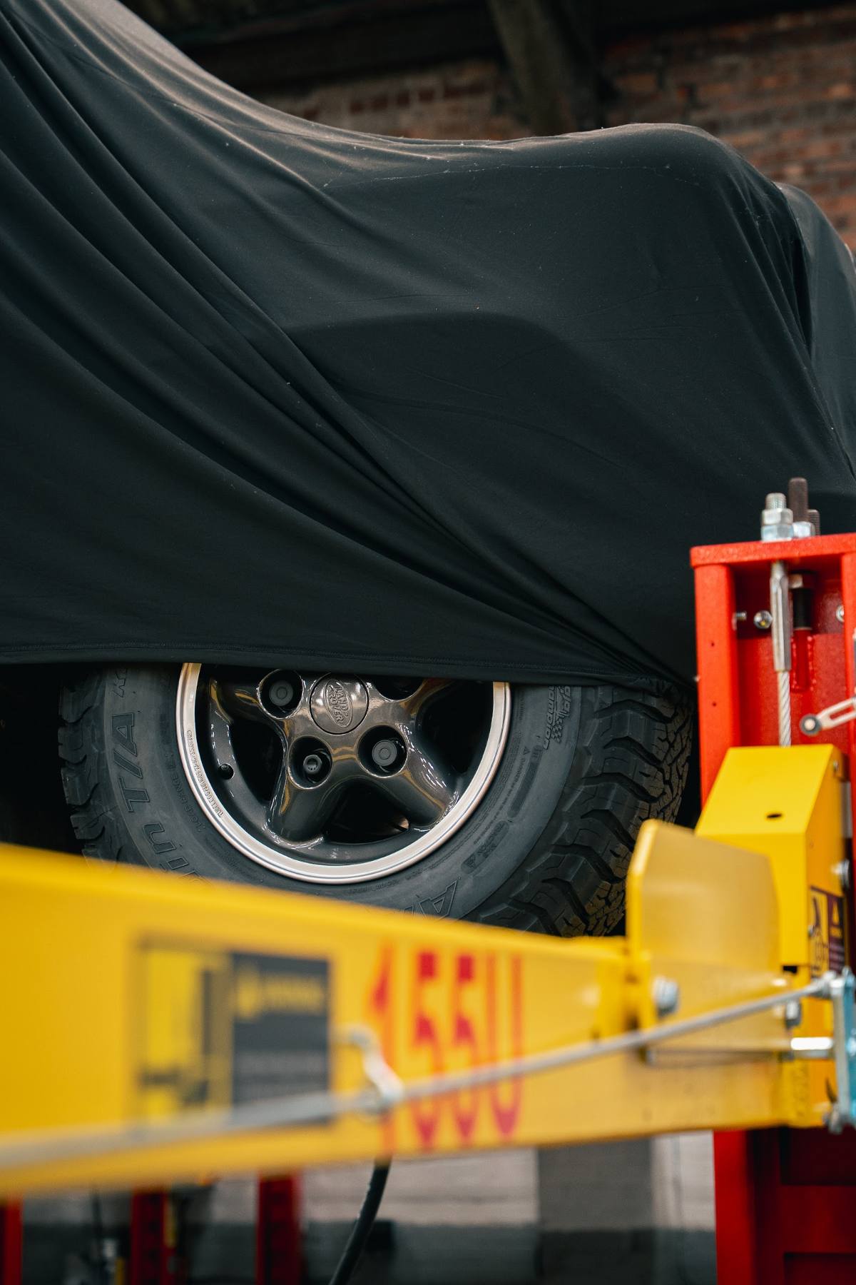 Close-up of a covered car's wheel on a lift
