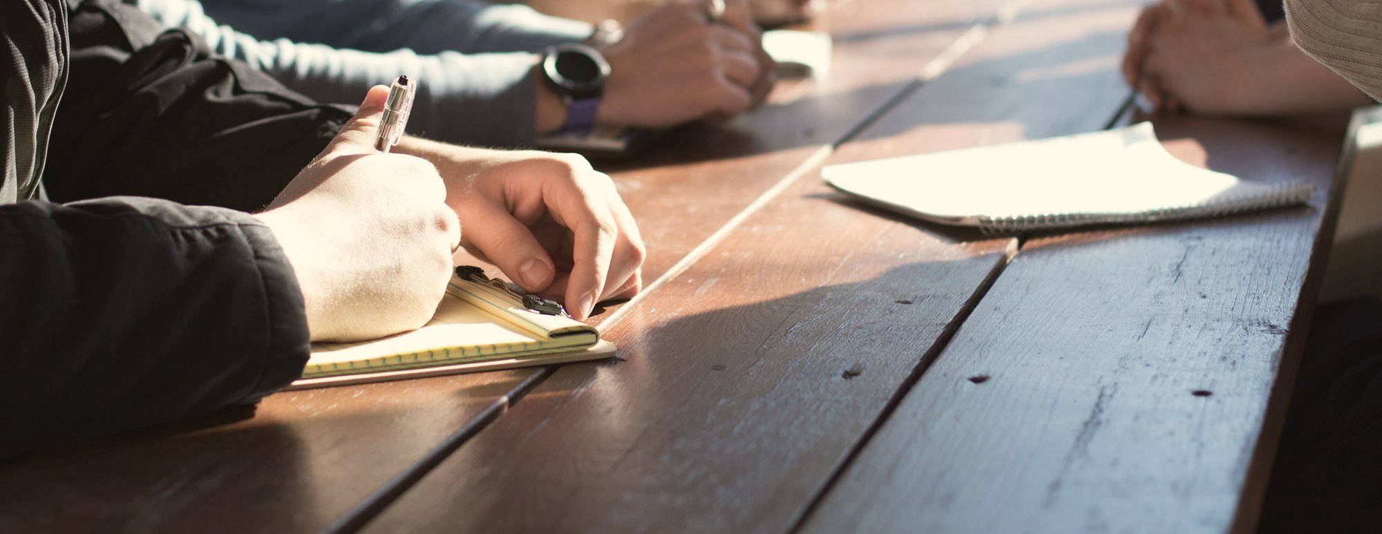 Team taking notes around a long wooden table